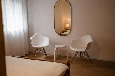 a bedroom with two white chairs and a mirror at Brodnik Apartment in Trbonje