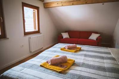 a bedroom with two beds with towels and a couch at 4 Sheeps Apartments in Bovec