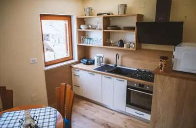a kitchen with white cabinets and a sink and a window at 4 Sheeps Apartments in Bovec