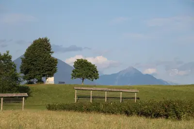 two benches in a field with mountains in the background at Studio Pr' Oreharjo in Zgornje Gorje