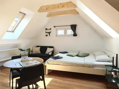 a attic bedroom with a bed and a table at Slovenian House Mira in Zgornje Gorje
