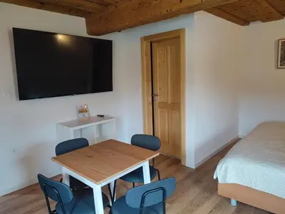 a room with a table and a bed and a flat screen tv at Slovenian House Mira in Zgornje Gorje
