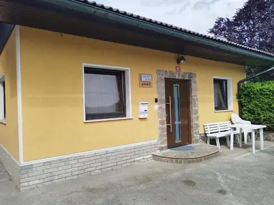 a yellow house with two chairs and a door at apartma Grad in Motnik