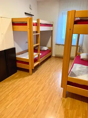 a room with three bunk beds and a wooden floor at Hostel Vrba in Ljubljana