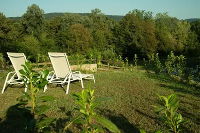 two white chairs sitting in the grass in a field at Mala Vila Kolpa in Griblje