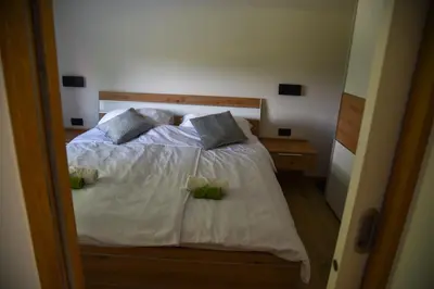a bedroom with a bed with white sheets and pillows at Mala Vila Kolpa in Griblje