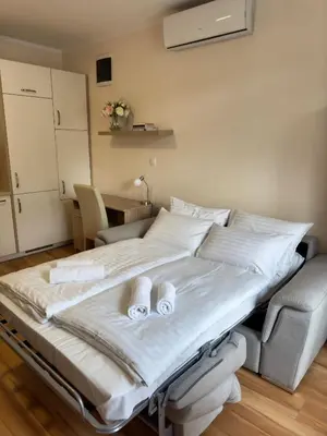 a large bed with white sheets and shoes on it at Cozy Corner Ljubljana in Ljubljana