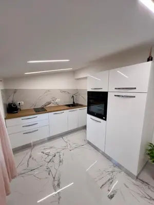 a kitchen with white cabinets and marble flooring at APP Krofek in Zgornje Škofije