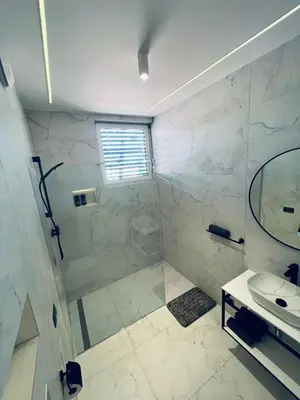 a white bathroom with a shower and a sink at ApartmaSLB in Slovenska Bistrica