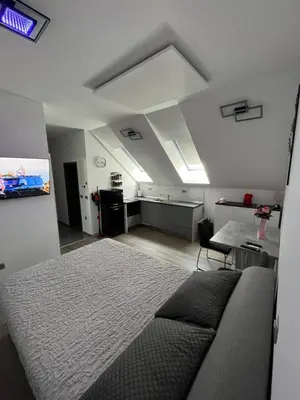a bedroom with a large bed and a kitchen at ApartmaSLB in Slovenska Bistrica