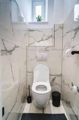 a white toilet in a bathroom with marble walls at HL Apartments in Maribor
