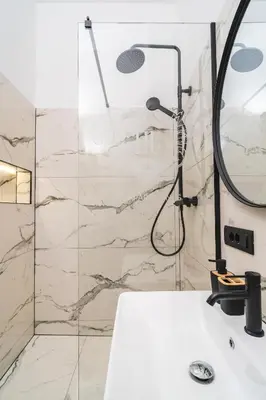 a bathroom with a shower and a white sink at HL Apartments in Maribor