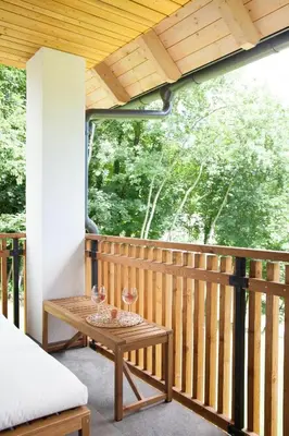 a porch with a table with two wine glasses on it at Mlino Alpino in Bled
