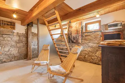 two chairs and a staircase in a room with a stone wall at Kolpa Holidays in Gradac