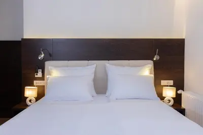 a white bed with two white pillows and two lights at Rooms Bella in Bled