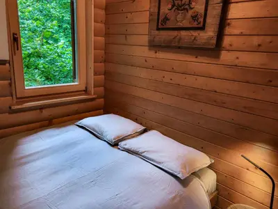 a bed in a wooden room with a window at Hillside Cottage in Bled
