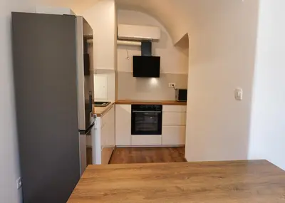 a kitchen with white cabinets and a wooden table at Apartments Metro 7 in Ljubljana