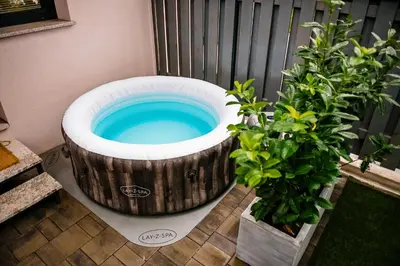 a wooden barrel bath tub sitting next to two plants at Apartment METULJ in Domžale
