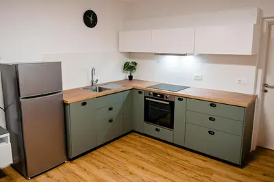 a kitchen with white cabinets and a stainless steel refrigerator at Apartment METULJ in Domžale