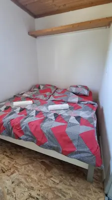 a bed in a room with a red and black quilt at Pool place in Petrovče