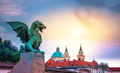 a statue of a green dragon in front of a building at Riverdance with mountain view, garden and private parking in Bled