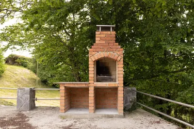 a brick oven sitting next to a fence at Roland House with Pool & Winery in Stara Vas-Bizeljsko
