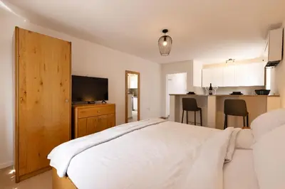a bedroom with a white bed and a kitchen at Roland House with Pool & Winery in Stara Vas-Bizeljsko