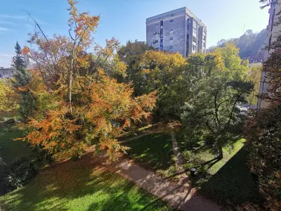 a park with trees and a building in the background at Apartment Studio MY RESIDENCE in the city center in Ljubljana