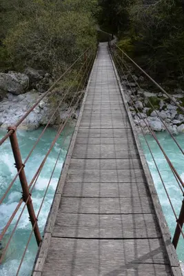 a wooden bridge over a river with blue water at Prosecco apartment in Bovec