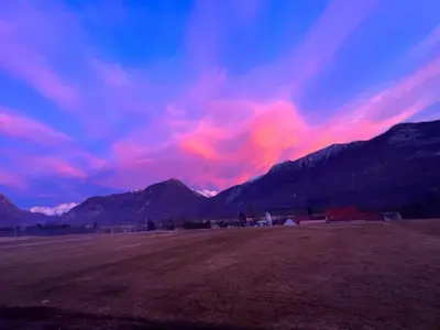 a sunset in a field with mountains in the background at Prosecco apartment in Bovec