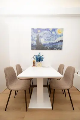 a white dining room table with chairs and a painting at MM NEW cozy modern apartment in Ljubljana