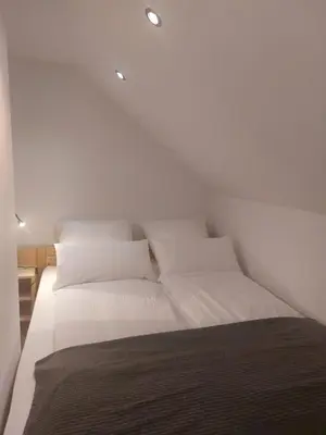 a bed with white sheets and pillows in a room at Ferienwohnung Bohinj in Bohinjska Bistrica