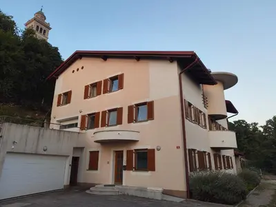 a large white building with a garage at Prenočišča Center Mir In Dobro in Solkan