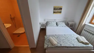 two beds in a small room with a bathroom at Prenočišča Center Mir In Dobro in Solkan