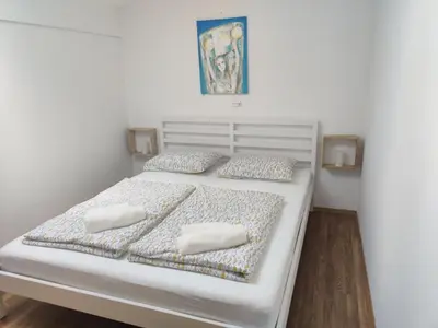 a white bed with two pillows on top of it at Prenočišča Center Mir In Dobro in Solkan