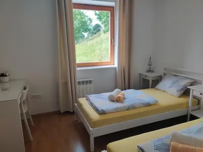 a small bedroom with two beds and a window at Prenočišča Center Mir In Dobro in Solkan