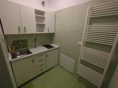 a small kitchen with white cabinets and green tiles at Prenočišča Center Mir In Dobro in Solkan