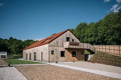 a large wooden barn with a red roof at Štajerska sivka - Jacuzzi & Savna in Maribor
