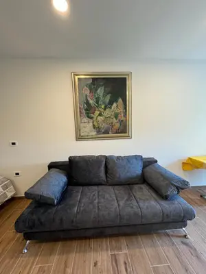 a couch in a living room with a painting on the wall at Apilandia Nanos in Vipava
