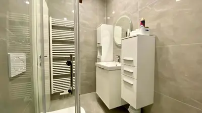 a white bathroom with a sink and a shower at Little Plaza Duplex in Ljubljana