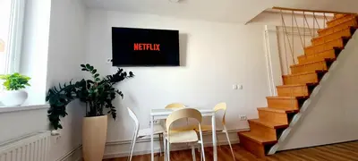 a dining room with a table and chairs with a television on the wall at Little Plaza Duplex in Ljubljana