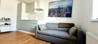 a living room with a couch and a kitchen at Little Plaza Duplex in Ljubljana