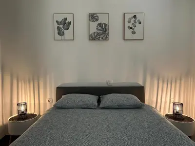 a bedroom with a bed and three pictures on the wall at AURORA Apartment Banovci in Banovci