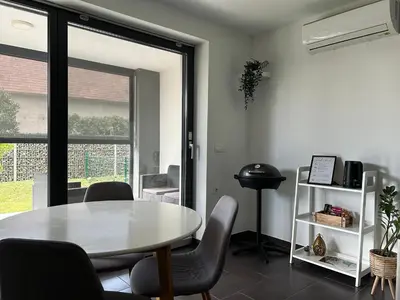 a dining room with a table and chairs and a window at AURORA Apartment Banovci in Banovci