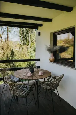 a patio with a wooden table and chairs and a window at Riverside House Krka in Zagradec