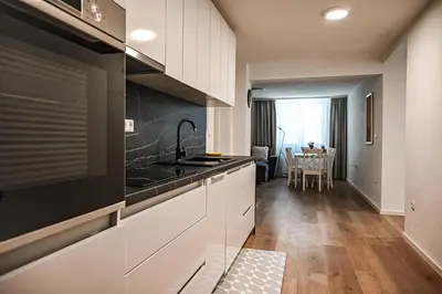 a kitchen with white cabinets and a table in the distance at Apartma Cave Bliss Maribor in Maribor