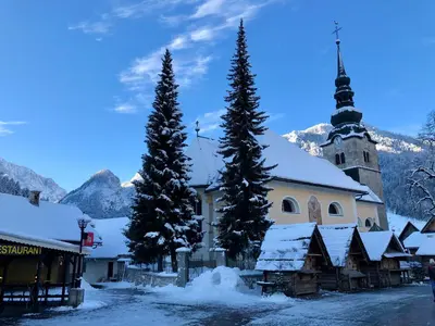 a church in the mountains with snow on the ground at Apartment Maya in Kranjska Gora