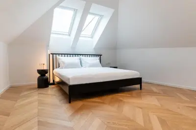 a bedroom with a bed with white sheets and two windows at Villa Elizabeth - Family Apartment for 6 in Slovenj Gradec