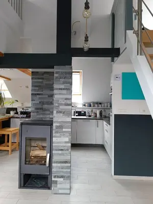 a kitchen with a fireplace in the middle of a room at Apartment Loft Pejić - open space loft studio near Bovec, Soča Valley in Bovec