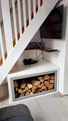 a fireplace under the stairs with logs in it at Apartment Loft Pejić - open space loft studio near Bovec, Soča Valley in Bovec